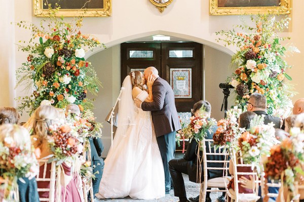 Bride and groom kiss at the top of the alter in front of guests