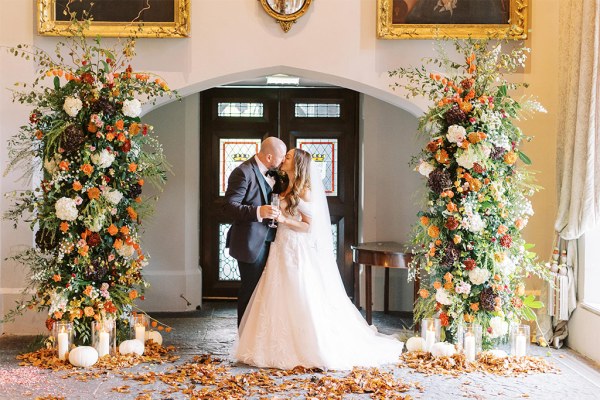 Bride and groom stand looking at each other flower beds either side of them