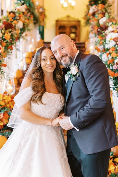 Bride and groom pose in front of stairs with pumpkins laid out