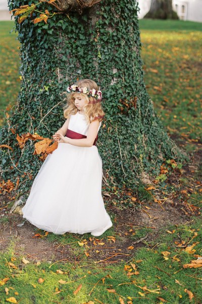 Little girl plays outside beside the tree in garden park