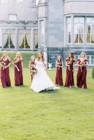 Bride walks ahead of the bridesmaids on grass