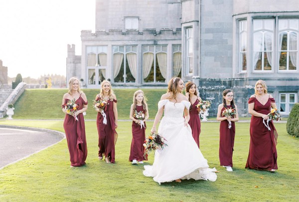 Bride walks ahead of the bridesmaids on grass