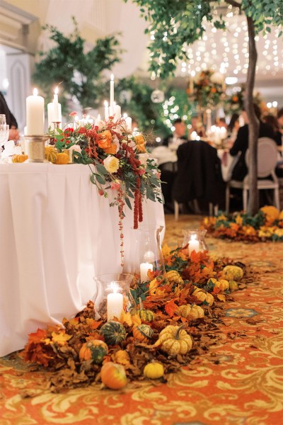 Pumpkins laid out on floor beside table covered in flowers