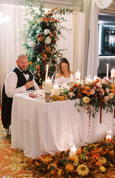 Bride and groom seated table covered in flowers K Fallon sign