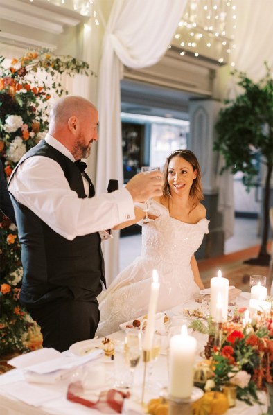 Bride and groom cheers with glasses of champagne at the table