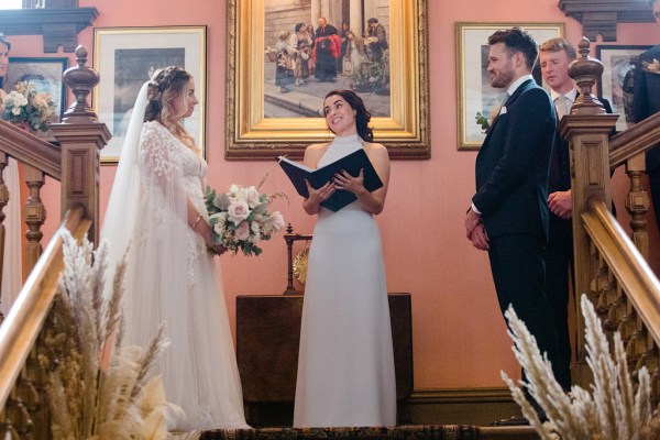 celebrant between bride and groom at top of staircase