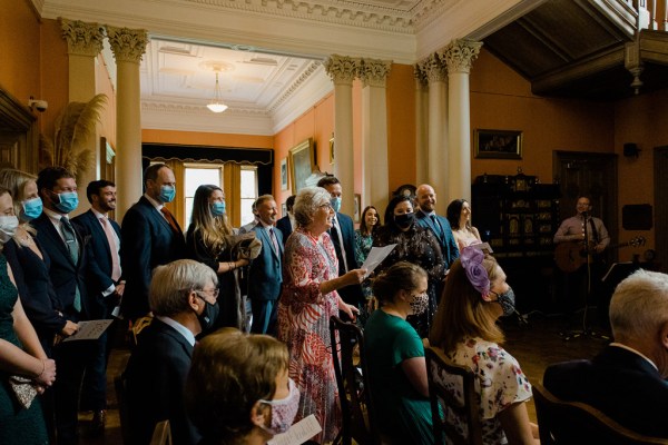 guests stand and watch bride and groom at top of staircase alter