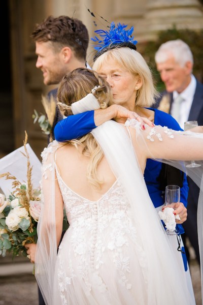 mother in blue dress hugs the bride