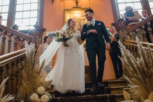 bride and groom make their way down the staircase together