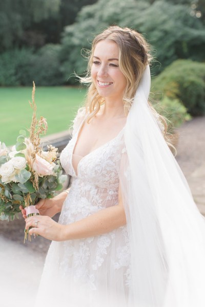 bride smiles on her own holding bouquet