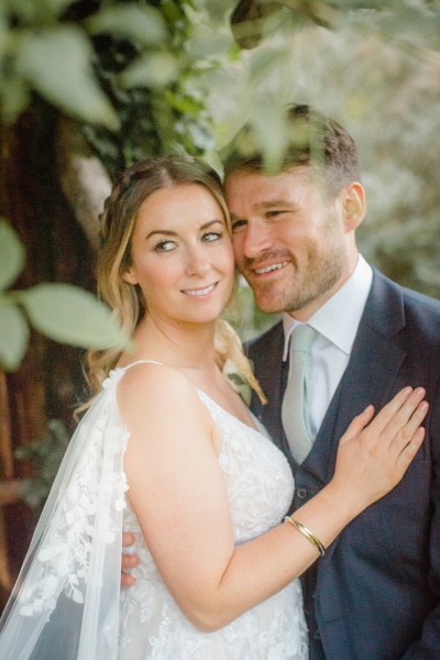 bride places hand on grooms suit jacket they smile