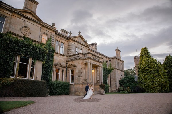 evening shot of bride and groom in courtyard holding hands