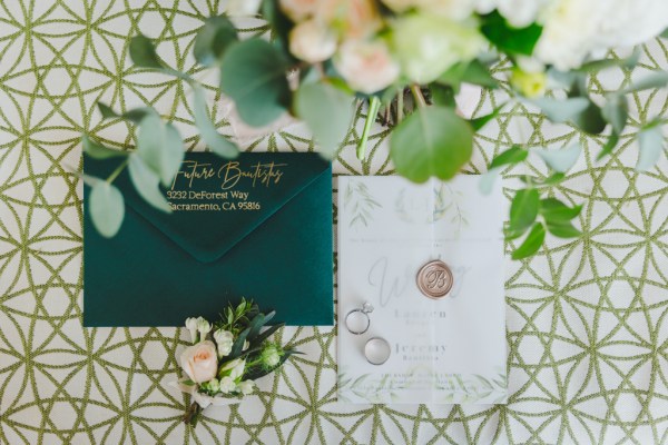 Green and white wedding invites on pattern tiles surrounded by pink flower