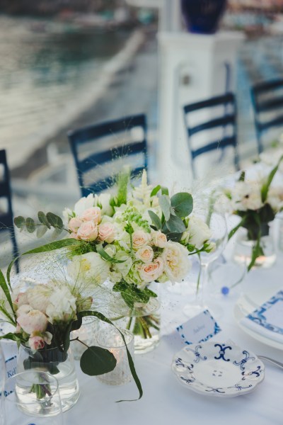 Pink and white flowers on a table with blue and white invites in an open-air restaurant