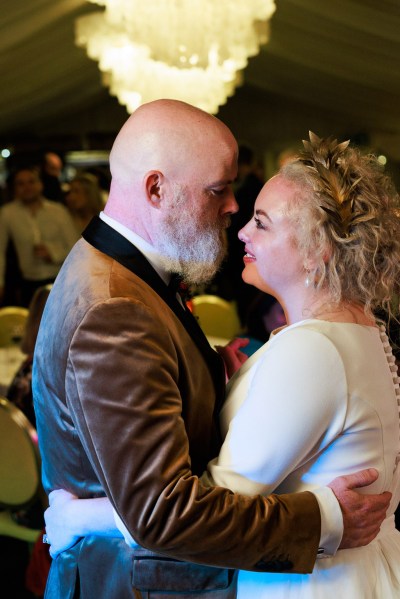 bride and groom dance on the dancefloor smiling at each other