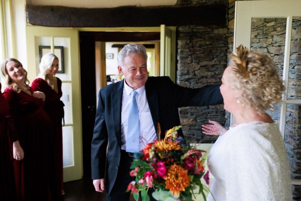 father of the bride goes in to hug his daughter as she holds bouquet