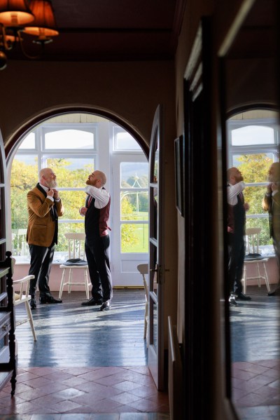 groom and groomsman are getting ready beside window