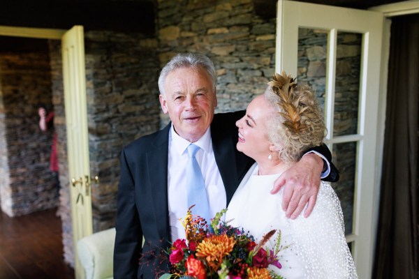 father of the bride goes in to hug his daughter as she holds bouquet