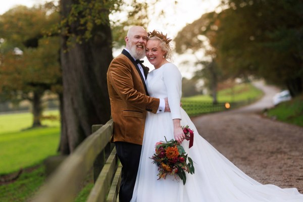 bride and groom against gate to forest setting