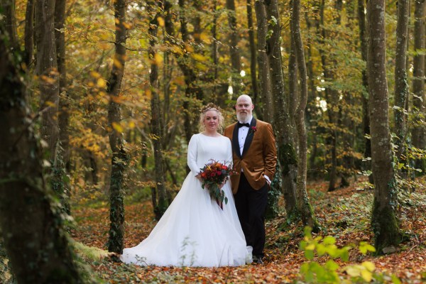 bride and groom stand inside forest surrounded by trees autumnal vibe