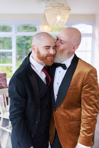 groom kisses groomsman on the cheek