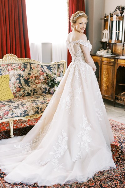 bride stands showing off long train dress in manor house stately room