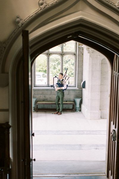 groom getting ready beside large window archway in shot