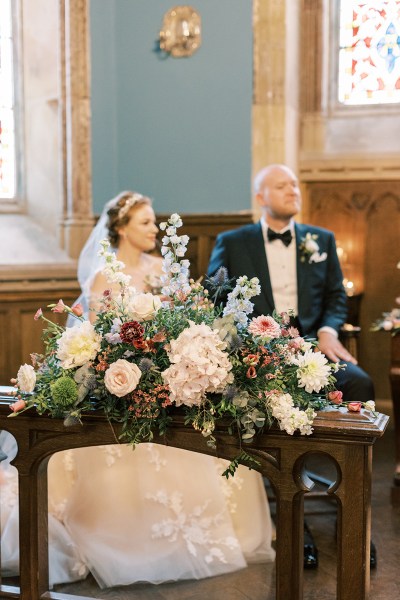 bride and groom sit at the alter signing marriage certificate