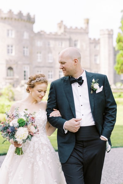 groom looks at bride as they walk outside in garden