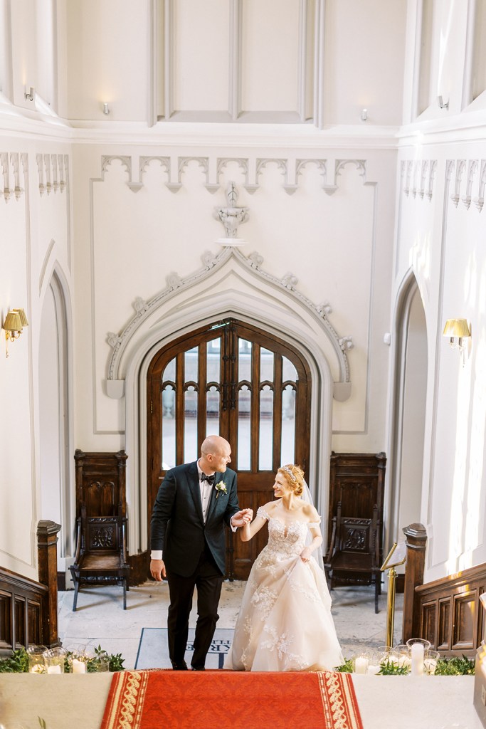 bride and groom walks up the staircase on red carpet