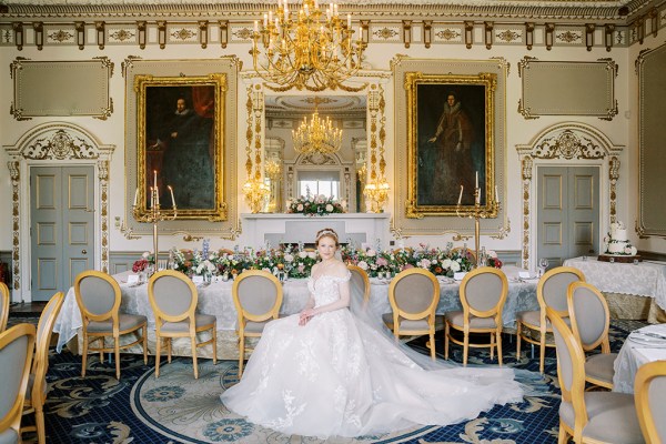 bride looks up hand over hand on lap shows off hair accessory dining room interior