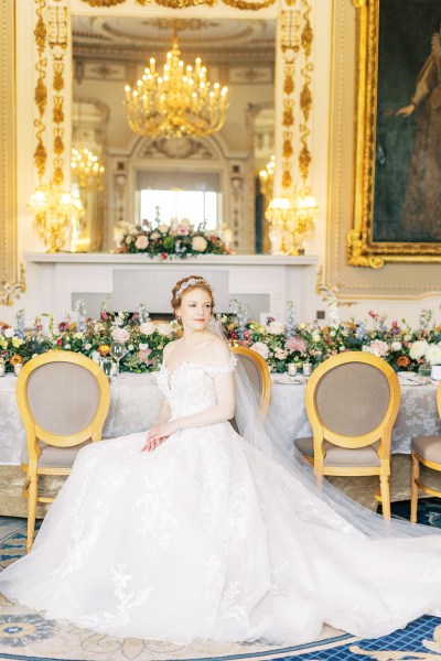 bride looks up hand over hand on lap shows off hair accessory dining room interior