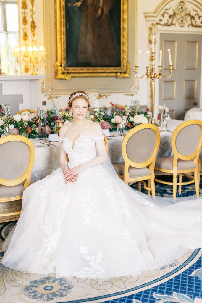 bride looks up hand over hand on lap shows off hair accessory dining room interior