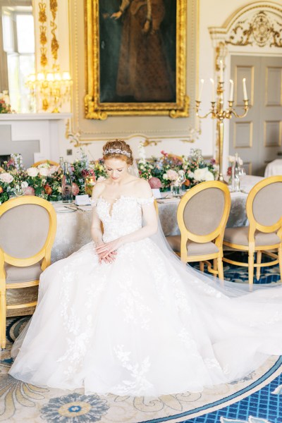 bride looks down hand over hand on lap shows off hair accessory