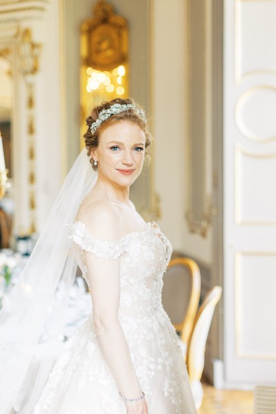 bride looks to her side and poses hair accessory and veil in shot