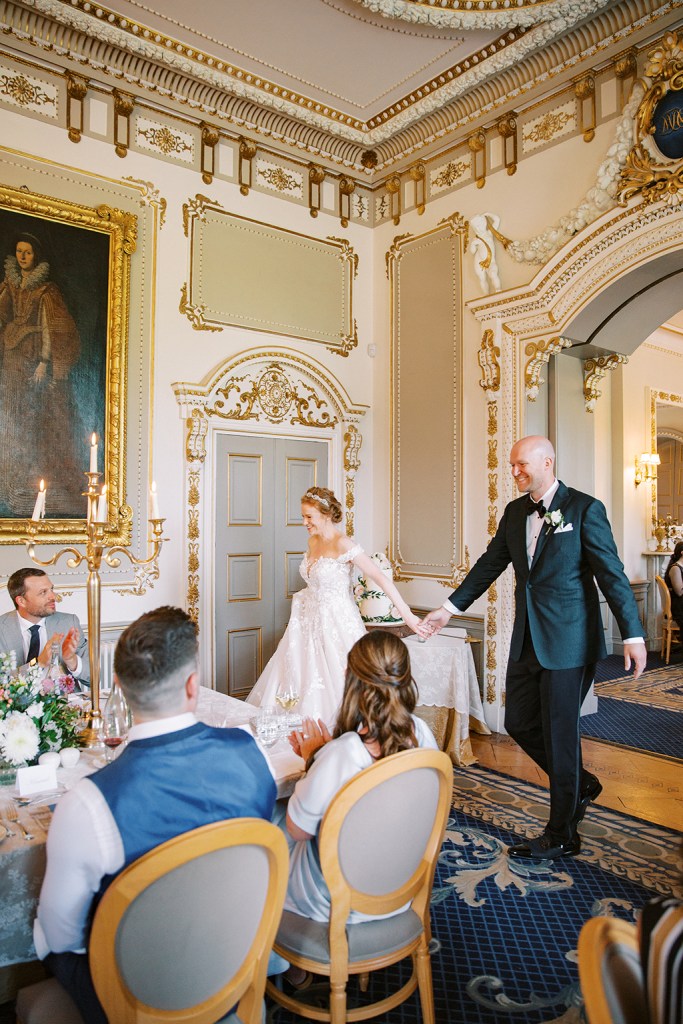 bride and groom enter ballroom setting guests clap they hold hands