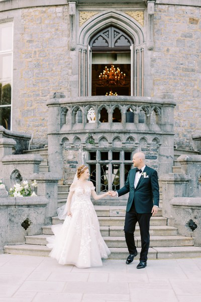 bride and groom walk down the venue steps and hold hands