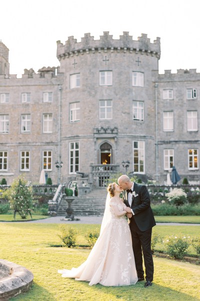 bride and groom kiss on the grass to venue wedding