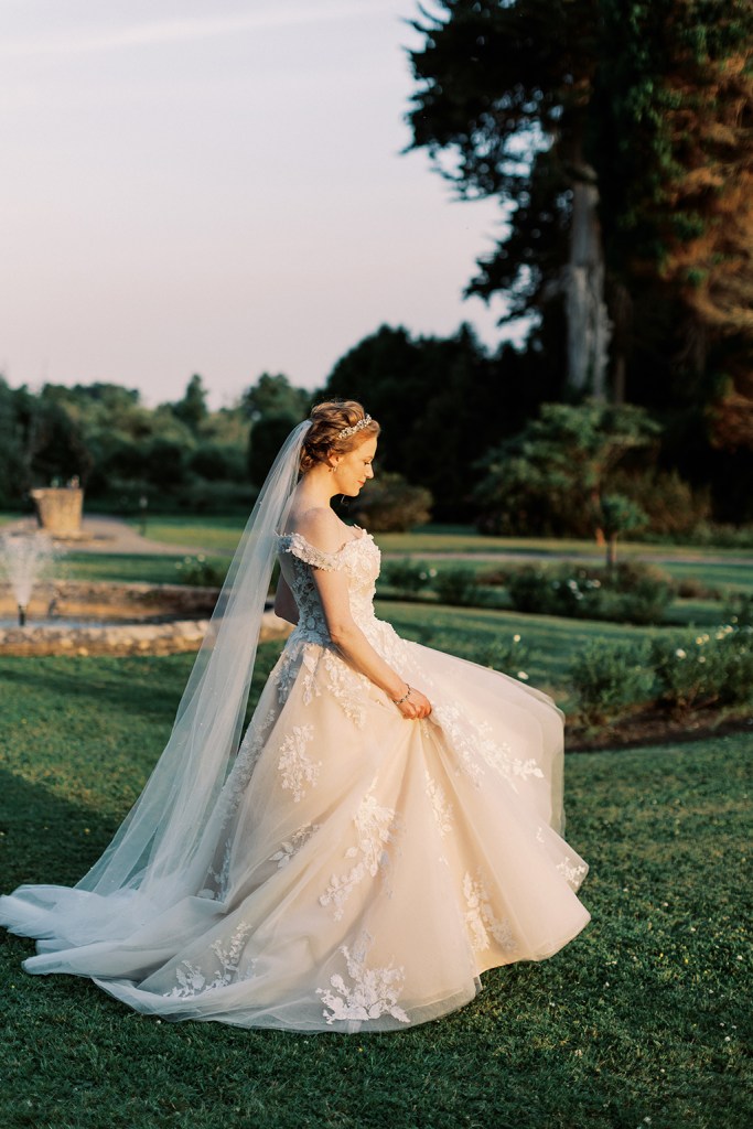 bride standing in garden trees fountain sun setting she walks