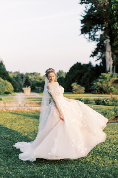 bride standing in garden trees fountain sun setting she dances on grass