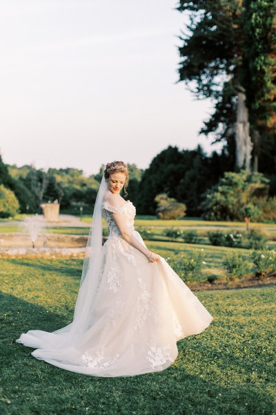 bride standing in garden trees fountain sun setting she dances on grass