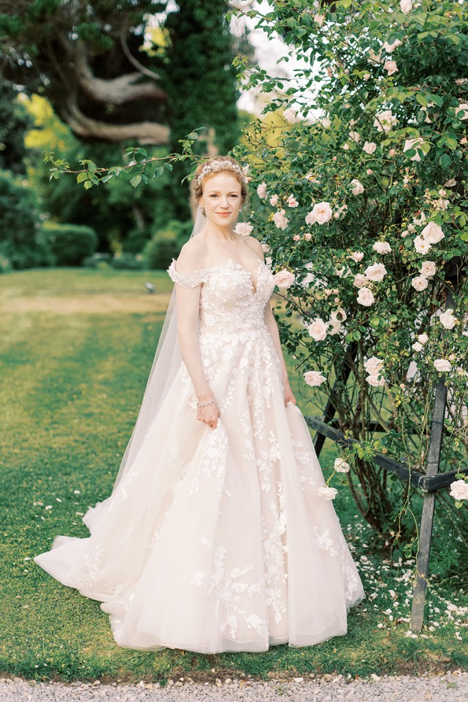 bride poses in garden beside flower bed