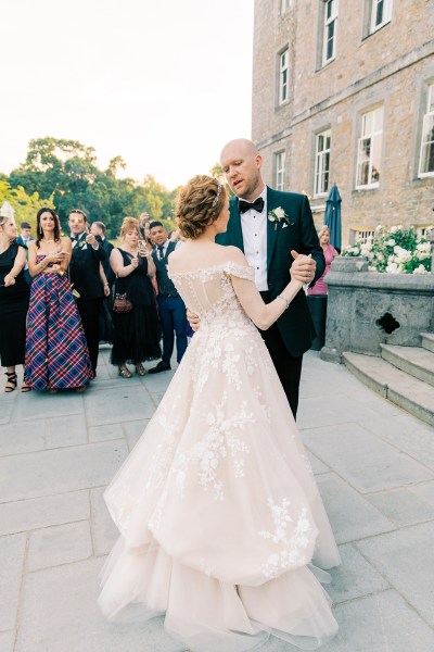 bride and groom dance in courtyard surrounded by guests