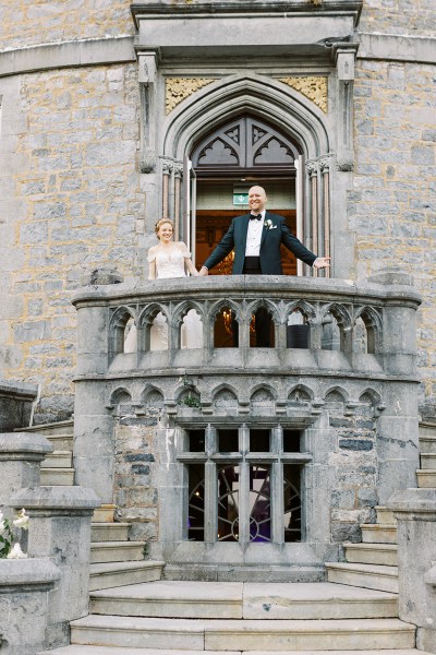 bride and groom stand on balcony setting castle wedding venue