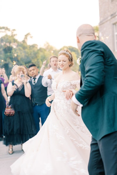 bride and groom hold hands and dance as guests clap