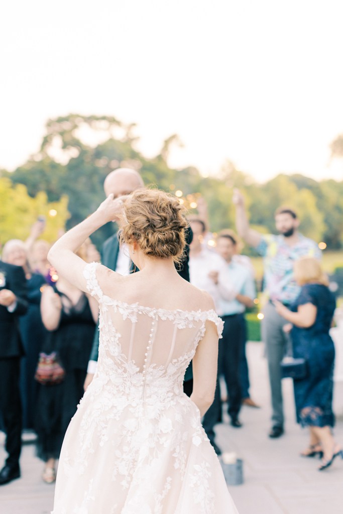 bride and groom hold hands and dance as guests clap