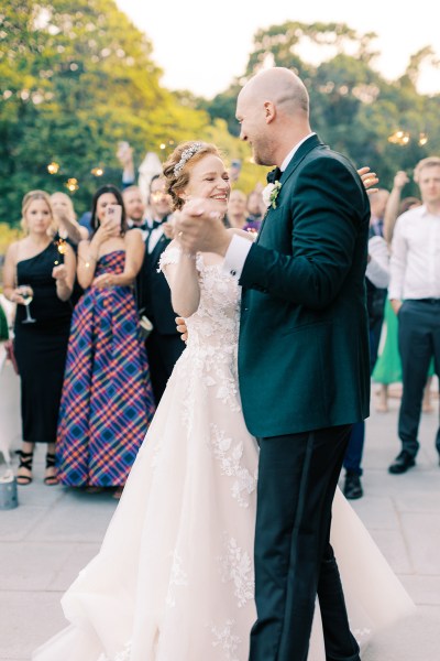 bride and groom hold hands and dance as guests clap