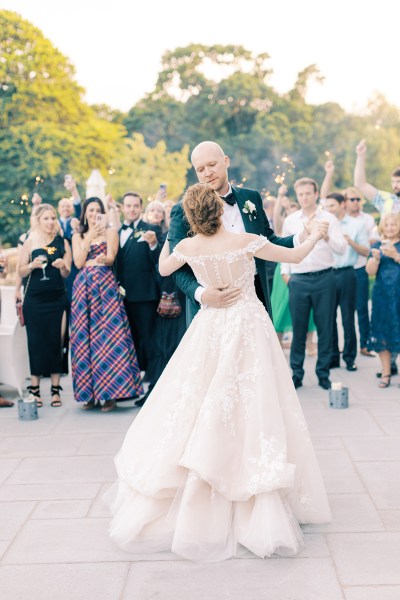 bride and groom hold hands and dance as guests clap