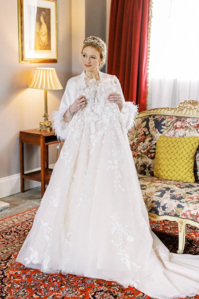 bride holds up bridal gown dress as she stands