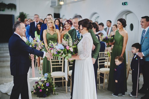 Bride stands at alter with father in front of guests